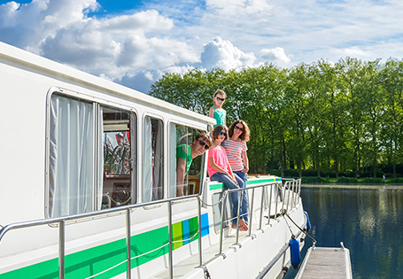 A smiling family standing aboard a houseboat