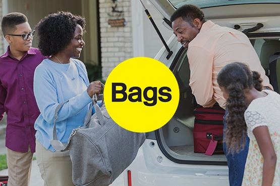 A Black family unloading the back of their car after a vacation