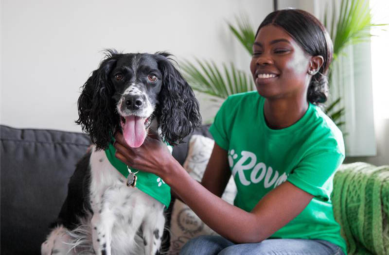 A Black woman in a Rover t-shirt on a couch with a dog