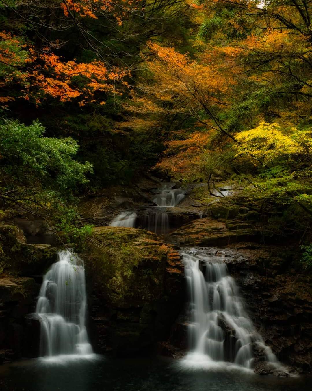 During autumn, the trees surrounding the waterfalls give the scene a vibrant hue.